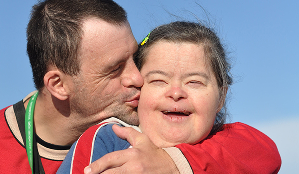Man with a disability kissing a woman with a disability.